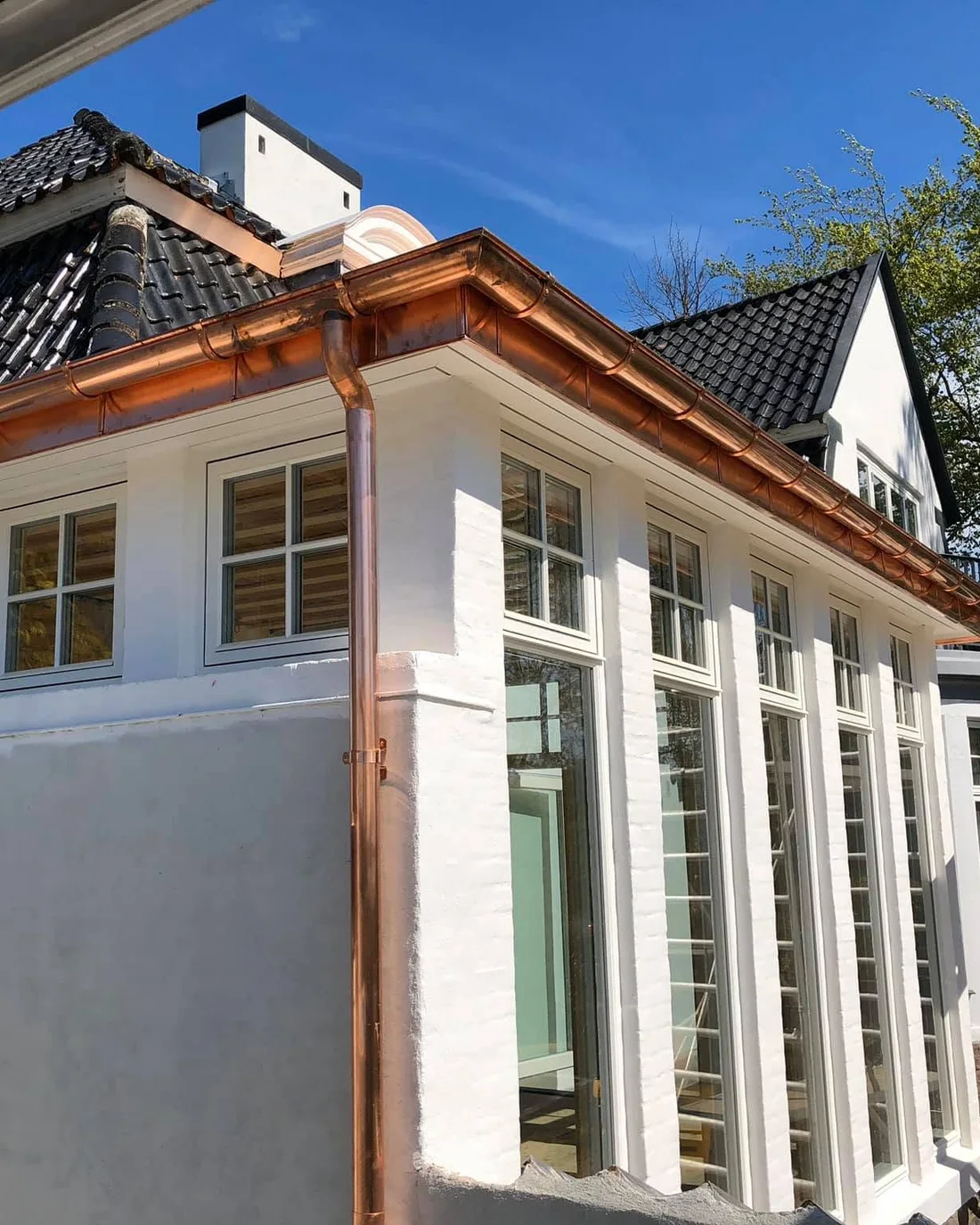 Ny kobbertagrende og kobbernedløb på et hvidpudset hus